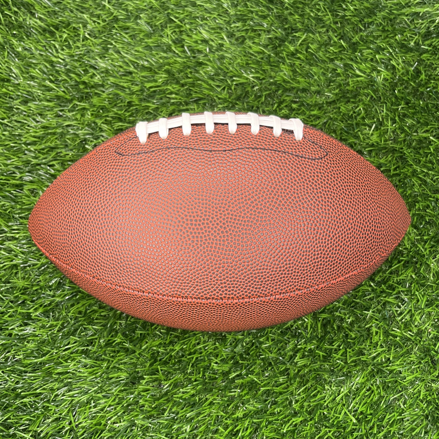 Brown Football Blank Non Branded Promotional Top Side on Grass Background