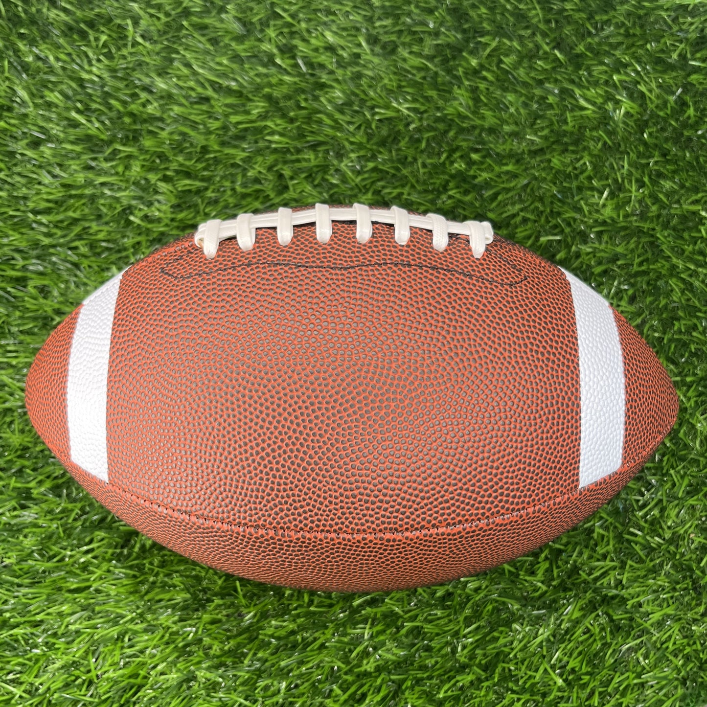Brown Football with Stripes Blank Non Branded Promotional Ball Top Side on Grass Background